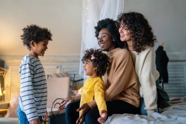 Mutlu çok ırklı aile evde birlikte vakit geçiriyor. Eşcinsel çift çocukları mutluluk kavramını sever