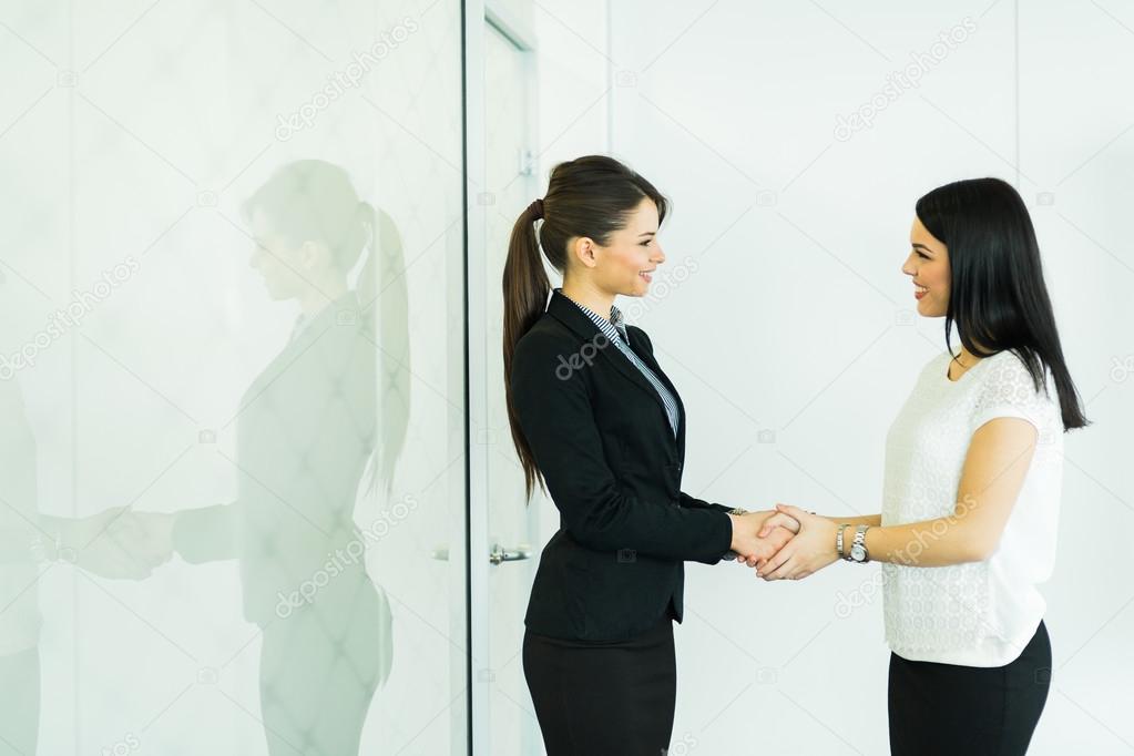 Two businesswomen shakig hands in an office