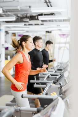 Bir grup insan bir spor salonunda koşu bandı kullanarak