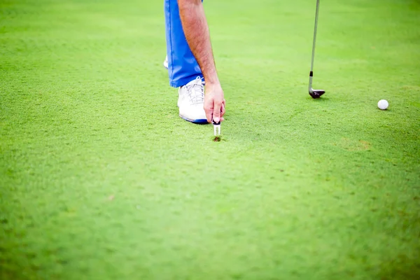 Joueur de golf réparant divot — Photo