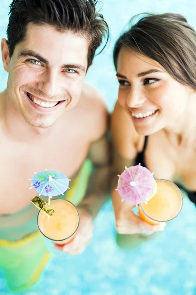 Pareja bebiendo un cóctel en una piscina — Foto de Stock