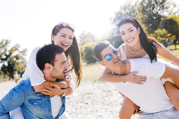 Pessoas felizes carregando mulheres em uma praia — Fotografia de Stock