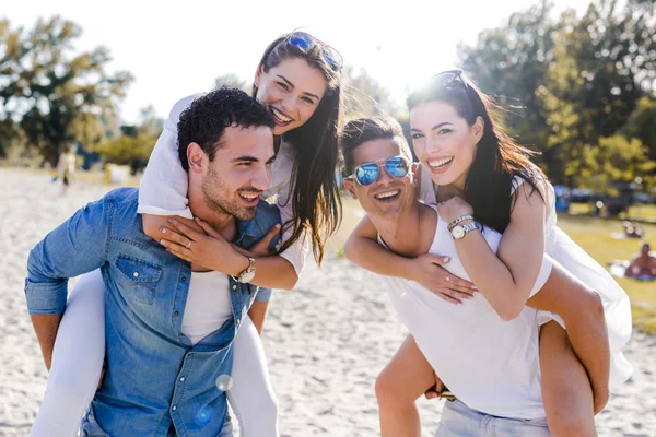 Счастливые люди несут женщин на пляже — стоковое фото
