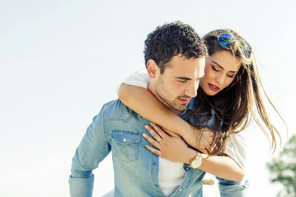 Handsome man carrying woman on his back — Stock Photo, Image