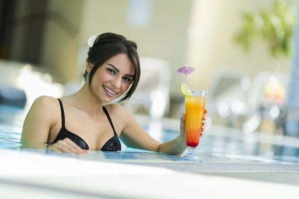 Lady drinking a cocktail in a swimming pool — Stock Photo, Image