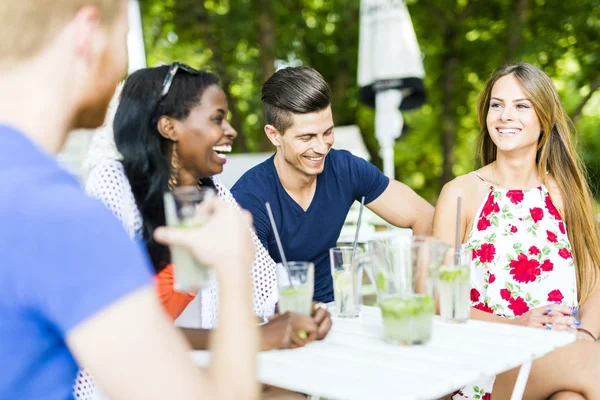 Happy vrienden zitten aan een tafel praten — Stockfoto