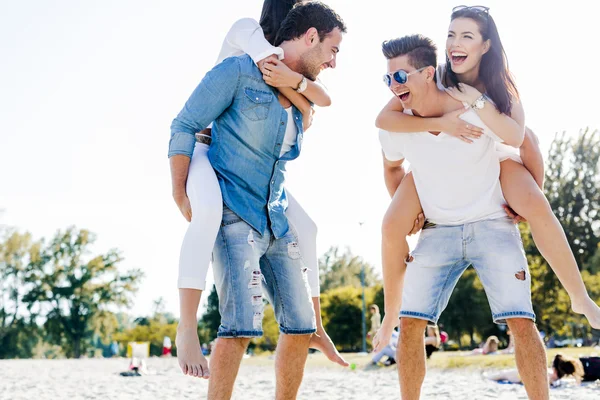 Pessoas felizes carregando mulheres em uma praia — Fotografia de Stock