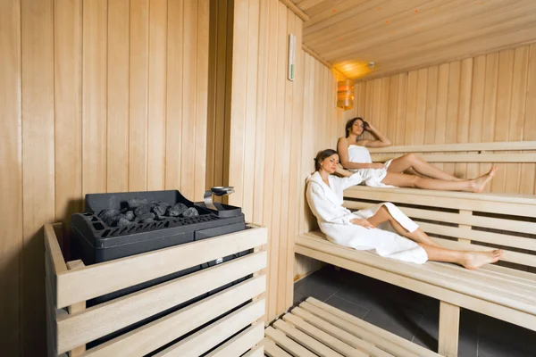Sauna heater and girls relaxing — Stock Photo, Image