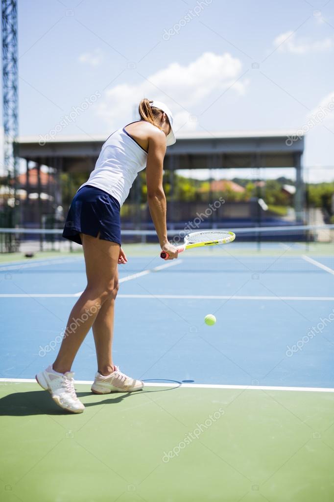 Beautiful female tennis player serving