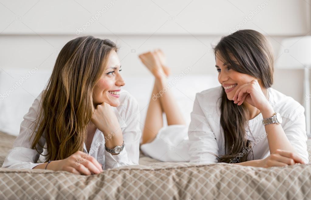 Two girls talking while lying on a bed — Stock Photo © nd3000 79076518