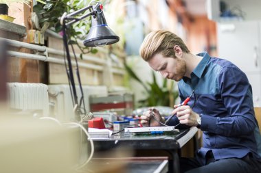 Handsome man soldering a circuit board clipart