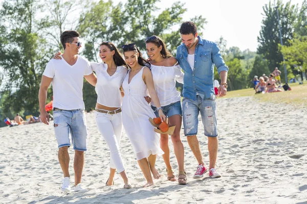 Grupp av unga människor höll händerna på stranden — Stockfoto