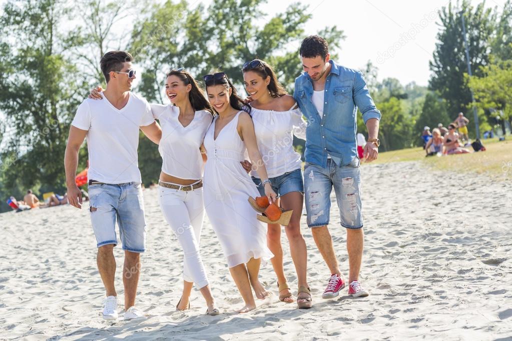 Group of young people holding hands on beach