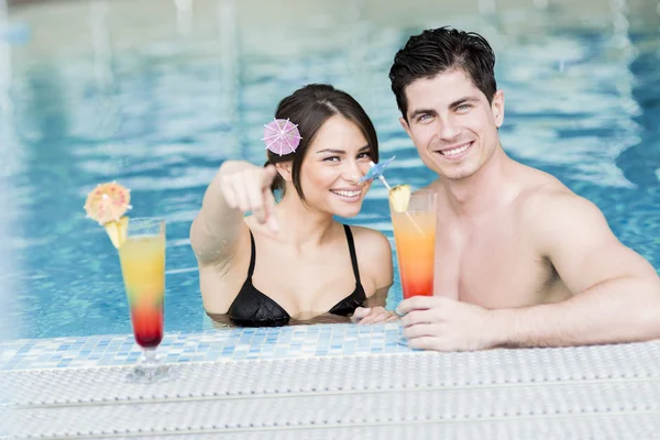 Pareja bebiendo un cóctel en la piscina — Foto de Stock