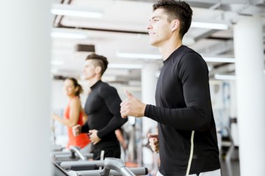 Bir grup insan bir spor salonunda koşu bandı kullanarak