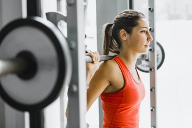 Kadın spor salonunda ağırlık kaldırıyor.
