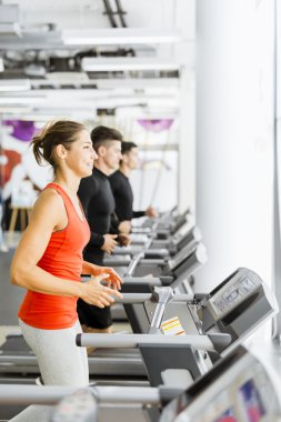 Bir grup insan bir spor salonunda koşu bandı kullanarak