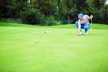 Golf oyuncu yeşil koyarak topa işaretleme