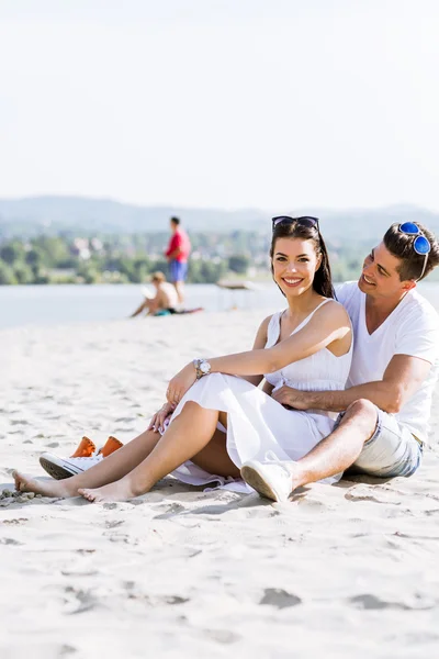 Romantiska unga paret sitter vid en strand — Stockfoto