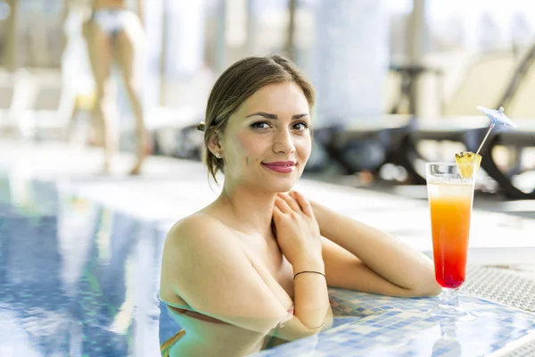Hermosa mujer en una piscina con un cóctel — Foto de Stock