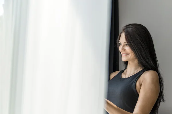 Gelukkige vrouw, starend uit het raam — Stockfoto