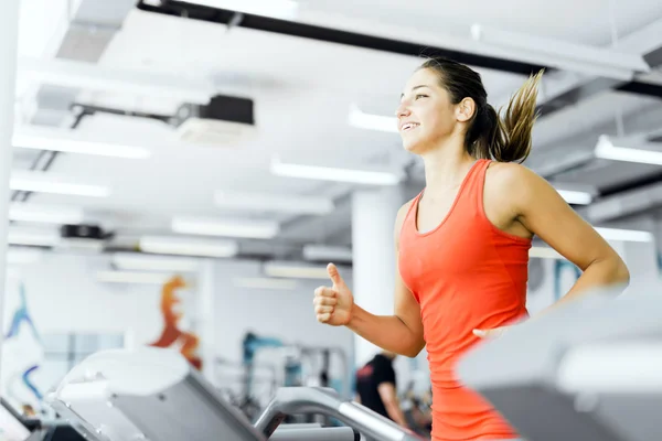 Vrouw wordt uitgevoerd op een loopband in de sportschool — Stockfoto