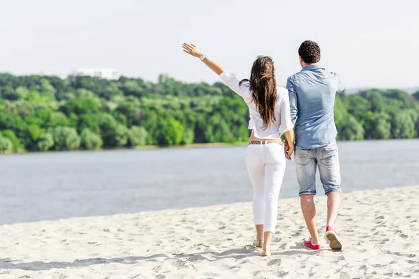 Пара тримає руки і ходить на пляжі — стокове фото