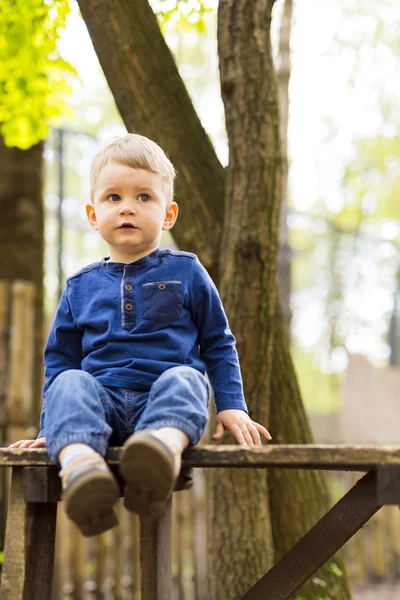 Ragazzino seduto su una panchina in un parco — Foto Stock