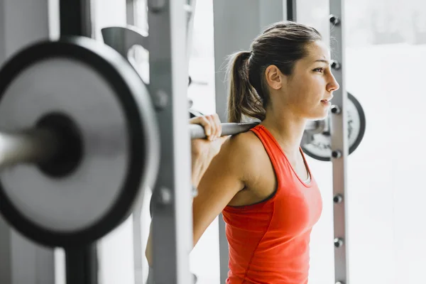 Femme soulevant des poids dans une salle de gym — Photo