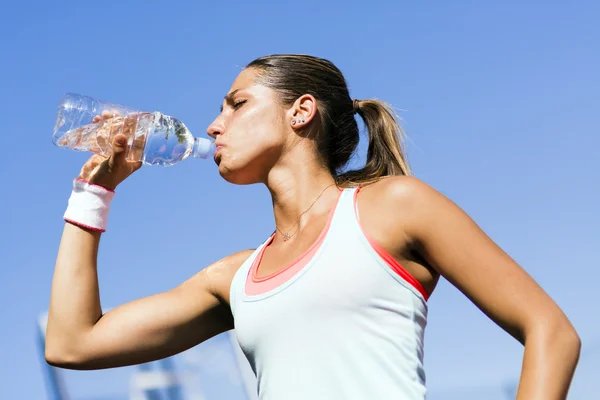 Athlete drinking water after exercising — Stock Photo, Image