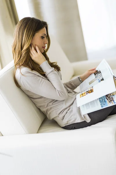 Mujer leyendo un periódico en la sala —  Fotos de Stock