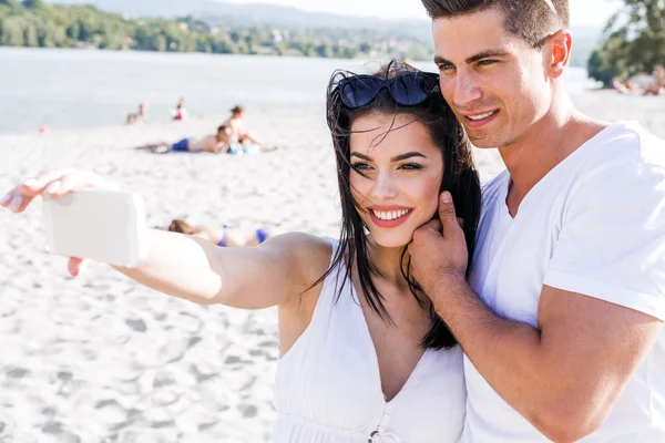 Casal tirando uma selfie de si mesmos em uma praia — Fotografia de Stock