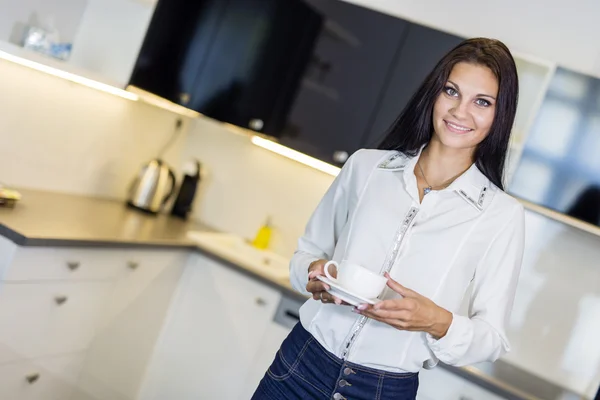 Hermosa mujer sosteniendo una taza en una cocina — Foto de Stock