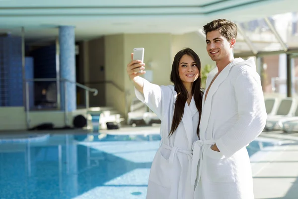 Couple amoureux debout à côté d'une piscine en peignoir — Photo