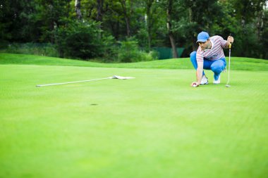 Golf oyuncu yeşil koyarak topa işaretleme