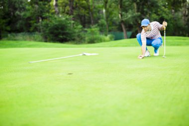 Golf oyuncu yeşil koyarak topa işaretleme