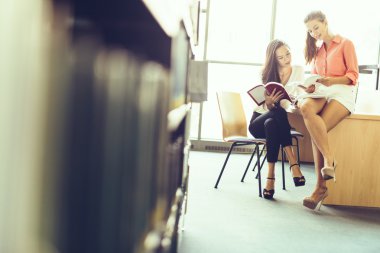 İki güzel öğrencilerin kütüphanede eğitim