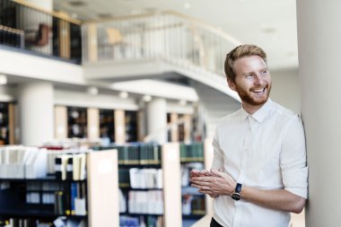 Yakışıklı öğrenci Kitaplığı'nda gülümseyen