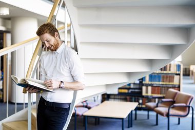 Öğrenci kütüphanede kitap okuyor.
