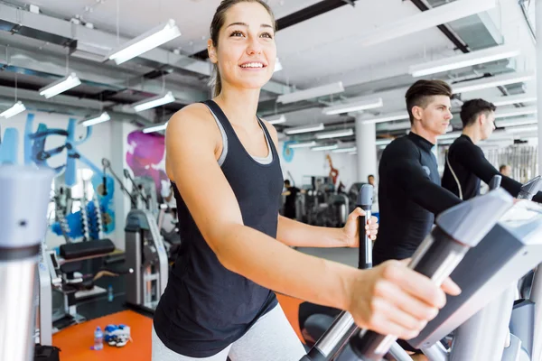 Young passar kvinnan med hjälp av en elliptisk tränare — Stockfoto