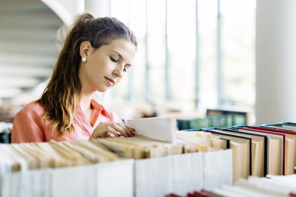 Student takes the right book off the shelf — Stockfoto