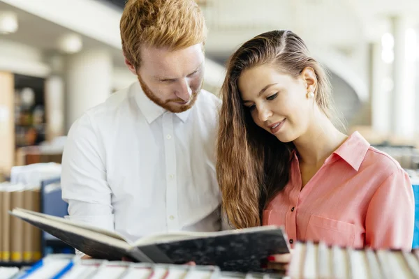 Dos estudiantes leyendo y estudiando en la biblioteca — Foto de Stock