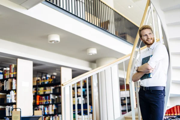 Student reading a book in a library — Stock Photo, Image