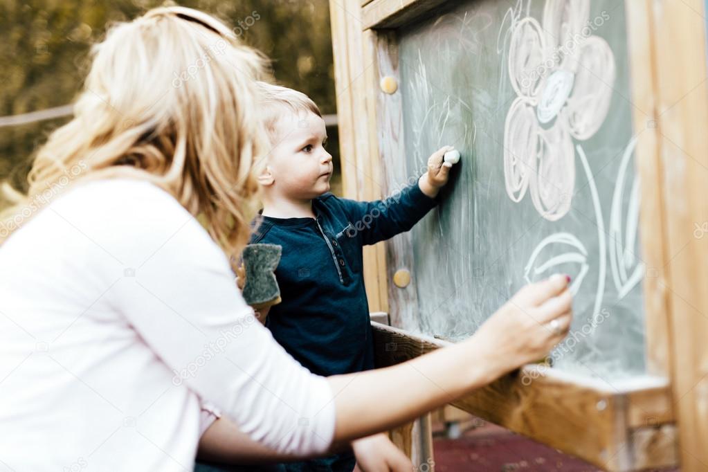 Mother and son drawing on blackboard with chalk