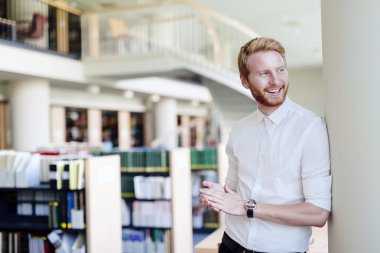 Yakışıklı öğrenci Kitaplığı'nda gülümseyen