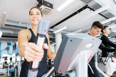 Eliptik bir eğitmen kullanan kadın genç yerleştirmek