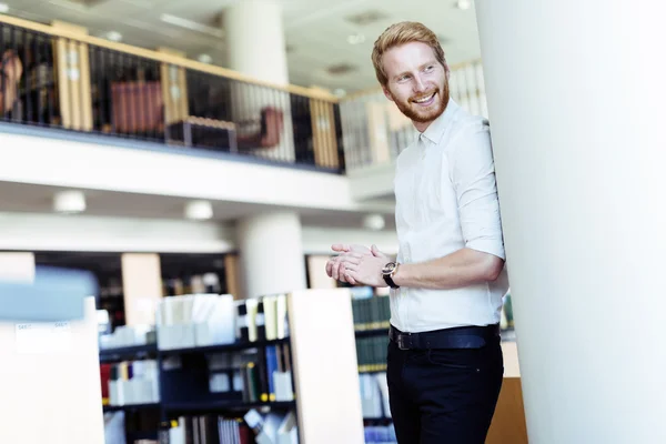 Estudante bonito sorrindo na biblioteca — Fotografia de Stock