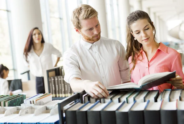 Dois estudantes lendo e estudando na biblioteca — Fotografia de Stock