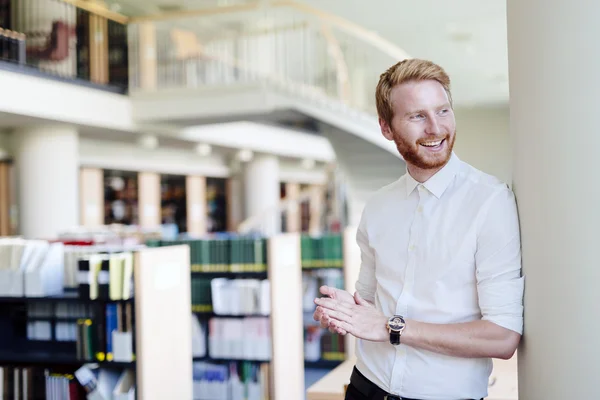 Estudante bonito sorrindo na biblioteca — Fotografia de Stock