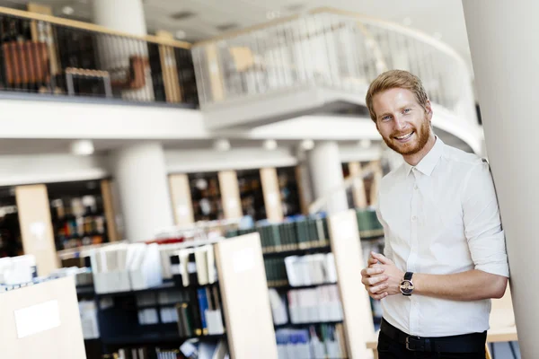 Handsome student smiling in library — Stock Photo, Image